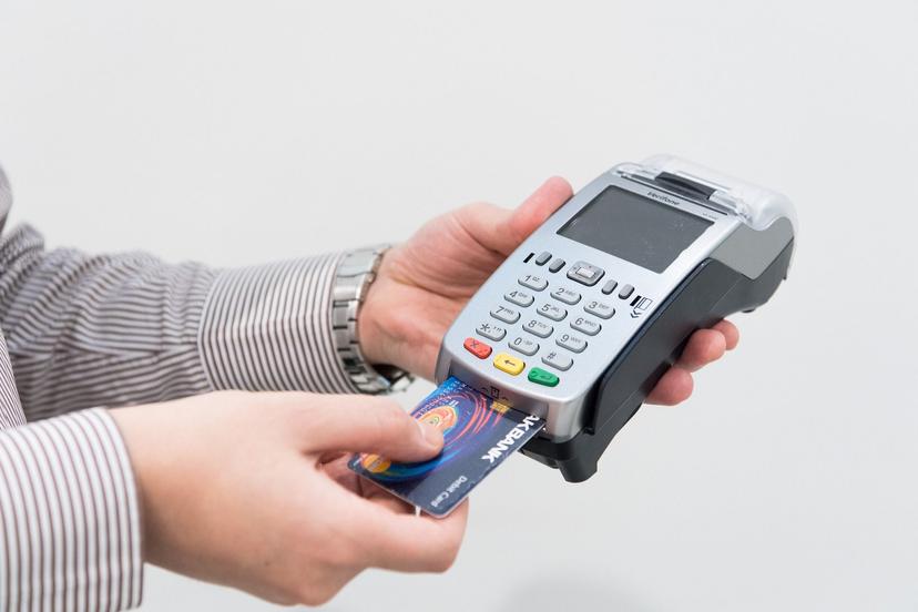 مرد یک دستگاه پوز و یک کارت بانکی در دست دارد