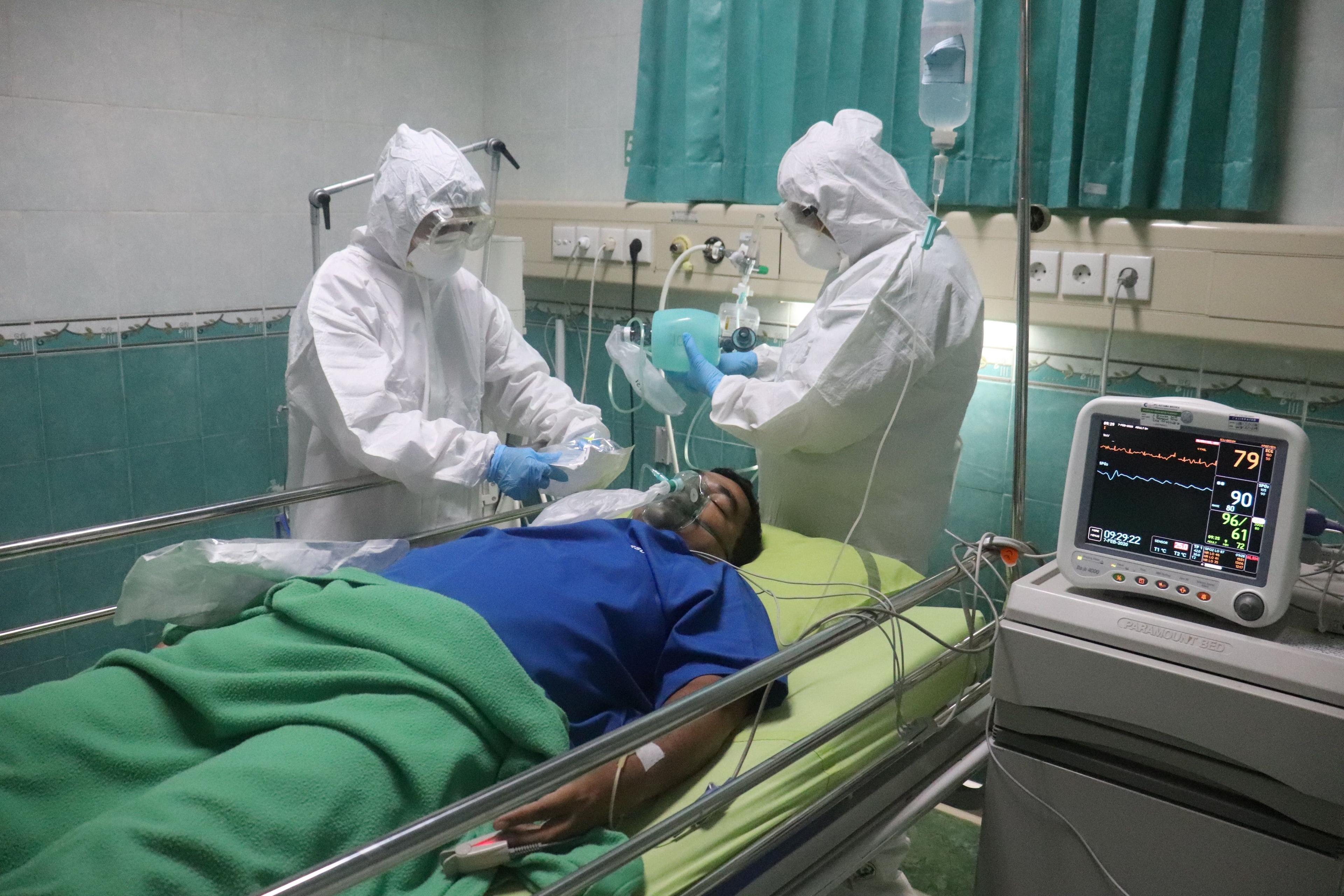 بیمار مبتلا به کووید روی تخت بیمارستان است و دو نفر از کادر درمان کنارش هستند